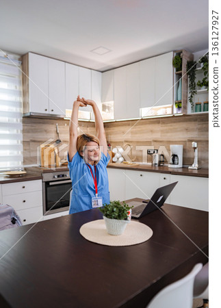 Female Doctor Stretching in her Kitchen after Online Meeting Female Doctor Stretching in her Kitchen after Online Meeting 136127927