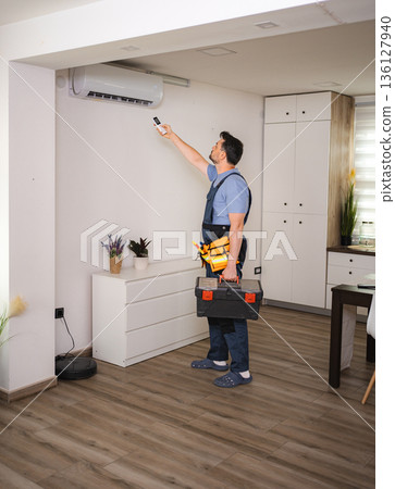 Technician installing and testing a new air conditioner unit in a modern apartment 136127940