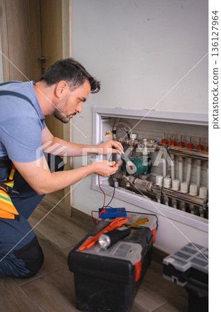 Technician checking domestic heating system with multimeter Technician checking domestic heating system with multimeter 136127964