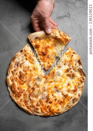 Hand taking slice of cheese pizza with melted cheese Hand taking slice of cheese pizza with melted cheese 136129015