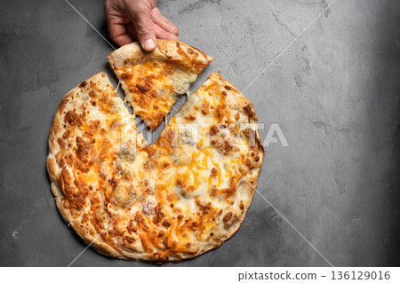 Hand taking slice of cheese pizza with melted cheese Hand taking slice of cheese pizza with melted cheese 136129016