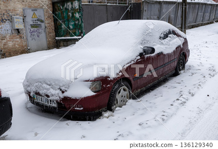 Urban winter scene with vehicle. Morning in city with graffiti and snowd vehicle. Snowy urban setting showcasing parked car and colorful wall art during morning hours 136129340