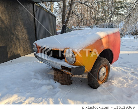 A frozen car hood. A vintage half-car left untouched on the street. An old part-car abandoned in the middle of a winter landscape. A rusty vintage car resting silently in a snowy landscape. A frozen car hood. A vintage half-car left untouched on the street. An old part-car abandoned in the middle of a winter landscape. A rusty vintage car resting silently in a snowy landscape. 136129369