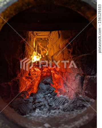 An antique brick fireplace glows with burning logs, creating a cozy and inviting atmosphere indoors. An antique brick fireplace glows with burning logs, creating a cozy and inviting atmosphere indoors. 136129383