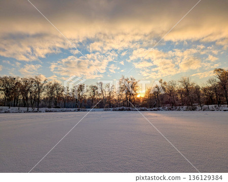 Sunset with orange clouds over a frozen winter lake Sunset with orange clouds over a frozen winter lake 136129384