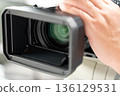 A man holding, operating and filming a video camera 136129531