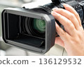 A man holding a video camera and operating the focus 136129532