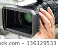 A man holding a video camera and operating the focus 136129533