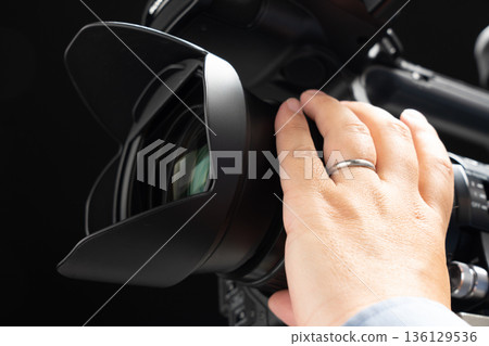 A man holding a video camera and operating the focus A man holding a video camera and operating the focus 136129536