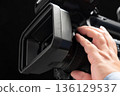 A man holding a video camera and operating the focus 136129537