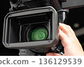 A man holding a video camera and operating the focus 136129539