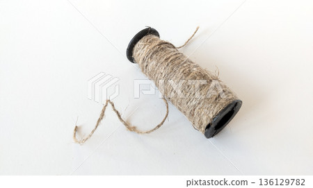 Spool of coarse jute rope wound on a black base. Stylish eco-material 136129782