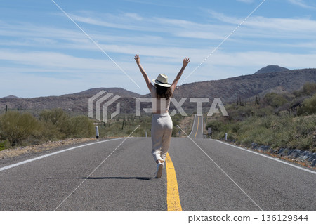 Tourist walking in the middle of a desert road enjoying freedom and adventure Tourist walking in the middle of a desert road enjoying freedom and adventure 136129844