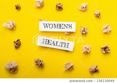 Yellow background with two pieces of paper that say Womens Health 136130049