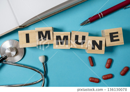 Immune health concept with wooden blocks, stethoscope, and red capsules on blue background Immune health concept with wooden blocks, stethoscope, and red capsules on blue background 136130078