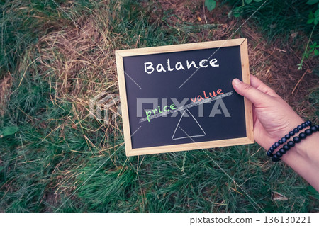 Person holds a chalkboard with the words balance and price value written on it Person holds a chalkboard with the words balance and price value written on it 136130221