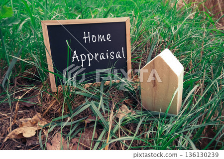 Home appraisal sign with wooden house model in lush green grass showcasing real estate concept Home appraisal sign with wooden house model in lush green grass showcasing real estate concept 136130239