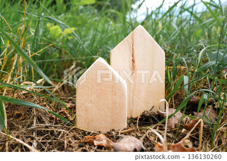 Two wooden houses are sitting on the ground in a grassy field 136130260