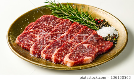 Fresh marbled beef slices arranged on a decorative plate with herbs and spices for culinary presentation 136130563