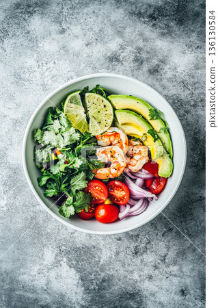 Fresh shrimp salad bowl with avocado, cherry tomatoes, lime, and herbs on a textured background Fresh shrimp salad bowl with avocado, cherry tomatoes, lime, and herbs on a textured background 136130584