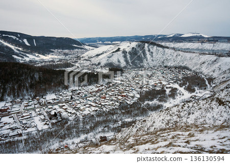 Aerial view of a snow covered village nestled in a valley with mountains and a river in winter. Landscape for travel, vacation spot. 136130594