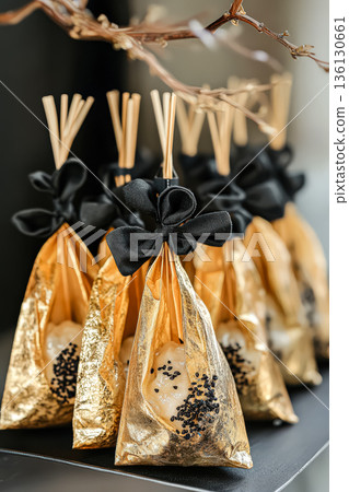 Bunch of gold and black bags with bows hanging from them Bunch of gold and black bags with bows hanging from them 136130661
