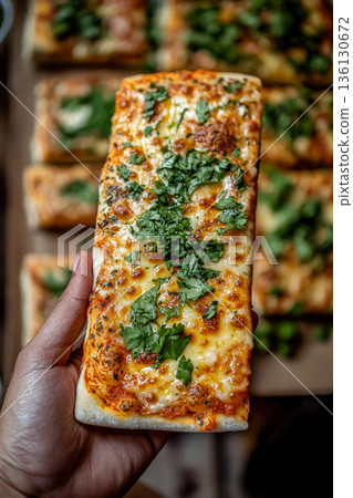 Person is holding a slice of pizza with green herbs on it Person is holding a slice of pizza with green herbs on it 136130672