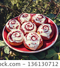 Plate of red and white cinnamon rolls with a white frosting swirl 136130712