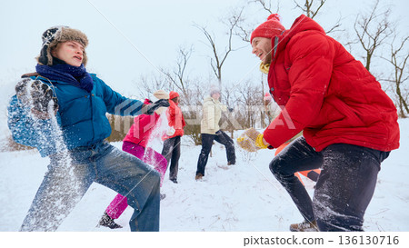 Friends throwing snow at each other during winter game outdoors. Friends throwing snow at each other during winter game outdoors. 136130716