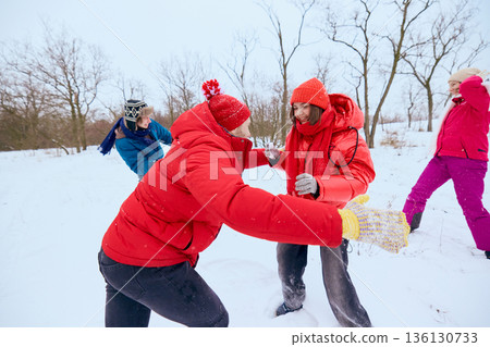 Young adults laughing during snow play outdoors. 136130733