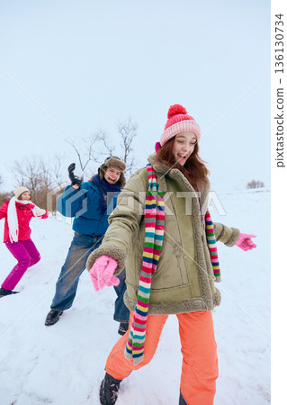 Friends laughing playing in snow during winter fun. Friends laughing playing in snow during winter fun. 136130734