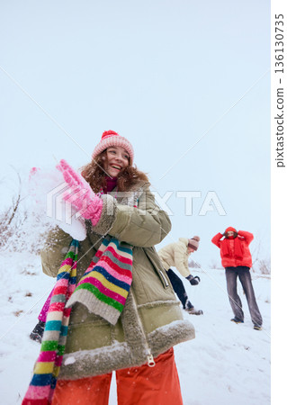 Young woman throwing snow during winter outdoor game 136130735