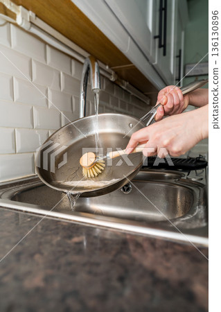Woman washing dishes, frying pan with eco friendly wooden brush for sustainable lifestyle Woman washing dishes, frying pan with eco friendly wooden brush for sustainable lifestyle 136130896