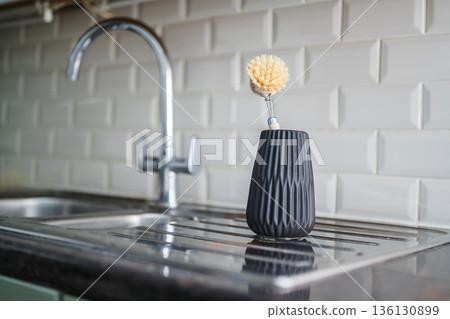 Sustainability concept. Wooden brush for washing dishes in the kitchen next to sink. Eco friendly, zero waste or conscious consumption concept. Sustainability concept. Wooden brush for washing dishes in the kitchen next to sink. Eco friendly, zero waste or conscious consumption concept. 136130899