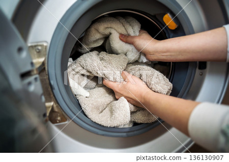 Washing machine at home. Smart appliances. Woman loading the washing machine with towels. Daily chores. Cleaning laundry 136130907