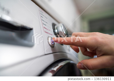 Washing machine. Pressing start button on modern washing machine display. Daily chores, close-up shot 136130911