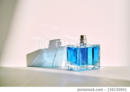 Blue glass perfume bottle creating abstract shadows Blue glass perfume bottle creating abstract shadows 136130941