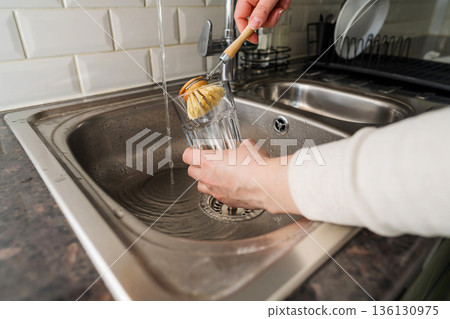Eco-friendly kitchen wooden brush. Woman washing dishes with bamboo brush. Waste-free, eco-friendly concept 136130975