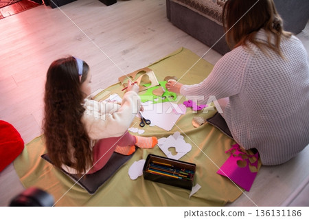 A child and adult create heart-shaped crafts together, using scissors, paper, and stencils. A fun and creative activity. 136131186