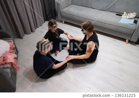 A family engages in a playful circle, sharing a moment of connection and fun. A family engages in a playful circle, sharing a moment of connection and fun. 136131225