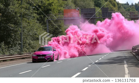 A glamorous pink car on the highway with pink smoke billowing out from underneath it 136131708