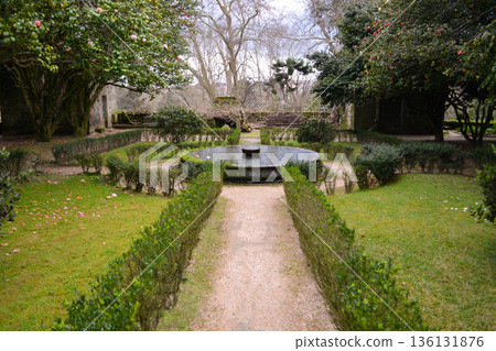 A path in a park in Vigo, northern Italy, with mature trees and spreading branches. The concept encompasses tourism, tranquility, relaxation, sustainable development, and urban green spaces. 136131876