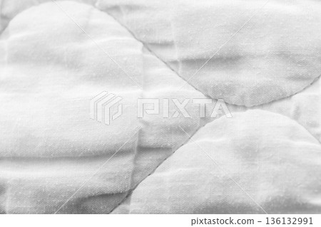 Macro photo of a white quilted fabric showing curved shapes and subtle stitching 136132991