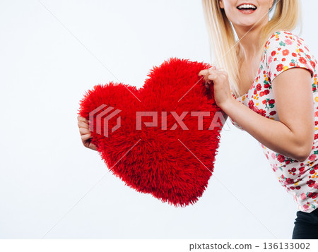 Happy woman holding heart shaped pillow Happy woman holding heart shaped pillow 136133002