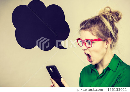 Angry business woman looking at phone, thinking bubble Angry business woman looking at phone, thinking bubble 136133021
