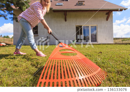 Unusual angle of woman raking leaves Unusual angle of woman raking leaves 136133076