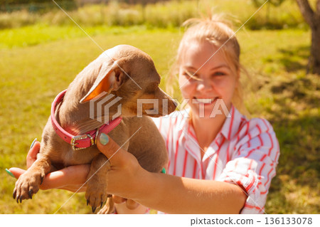 Woman playing pinscher ratter dog outside Woman playing pinscher ratter dog outside 136133078