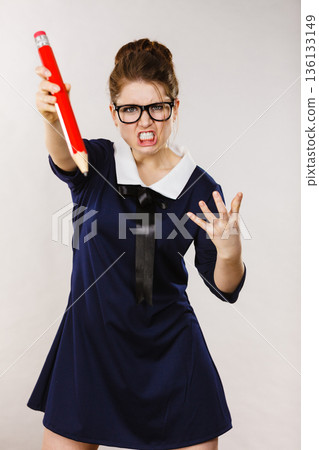 Angry woman holds big pencil in hand 136133149