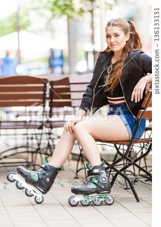 Young woman sitting wearing roller skates Young woman sitting wearing roller skates 136133151