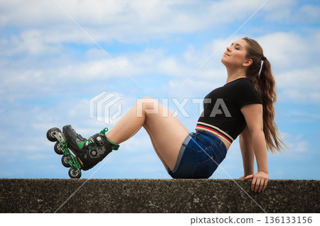 Happy young woman wearing roller skates Happy young woman wearing roller skates 136133156